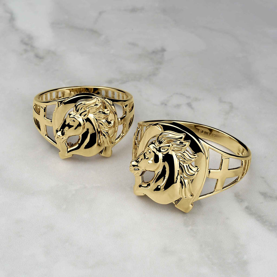 Two yellow gold horseshoe rings with a detailed horse head center on marble.