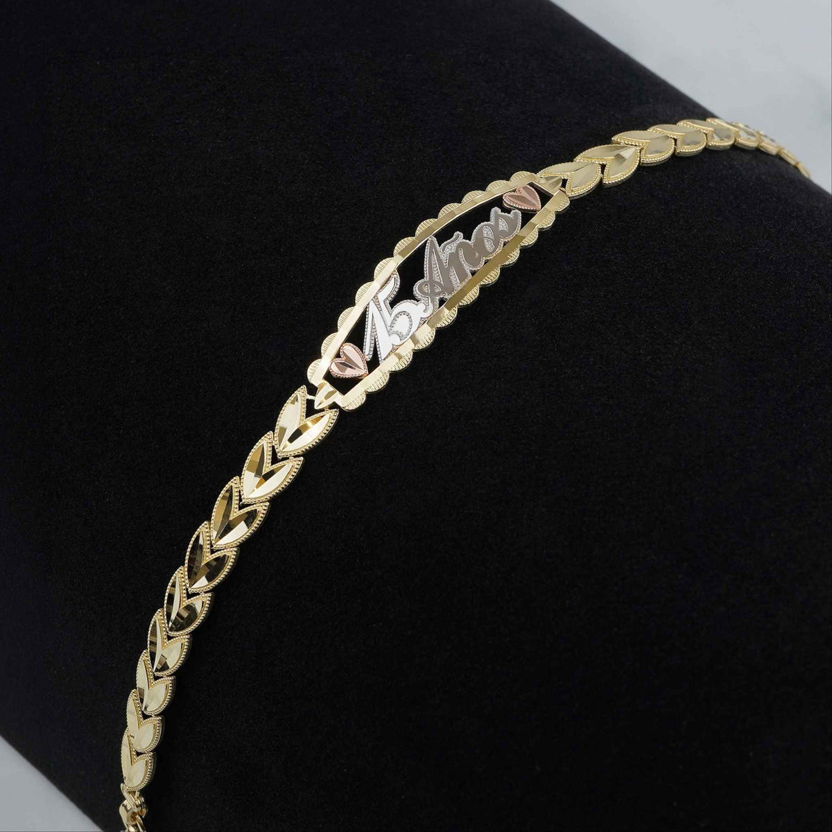 Tri-color gold Quinceañera "15 Años" leaf link bracelet displayed on dark background.