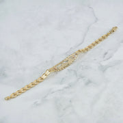 Back view of the tricolor gold Quinceañera leaf bracelet lying on a marble surface.