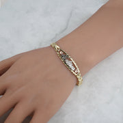 Close-up of the multi-tone gold "15 Anos" bracelet worn on a wrist.