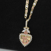Two-tone gold Quinceañera 15 heart pendant on a chain against a black background.