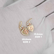 Two gold Quinceañera heart pendants in Sizes 1 and 2 with measurements displayed on fabric.