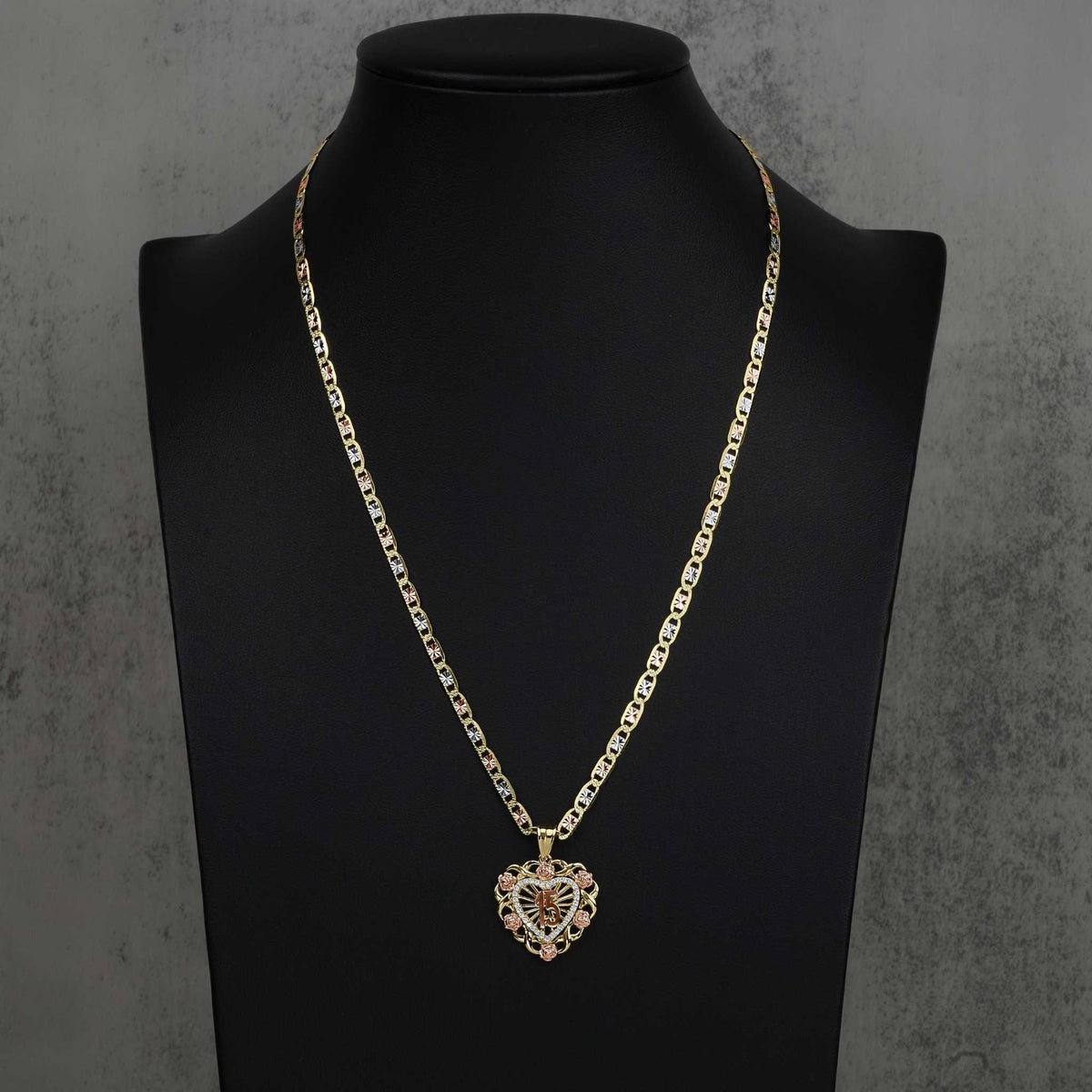 Two-tone gold 15th birthday heart pendant necklace presented on a dark display stand.