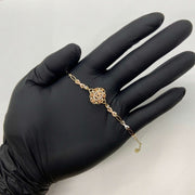 Gold Quinceañera 15th birthday rose motif charm bracelet displayed across an open hand.