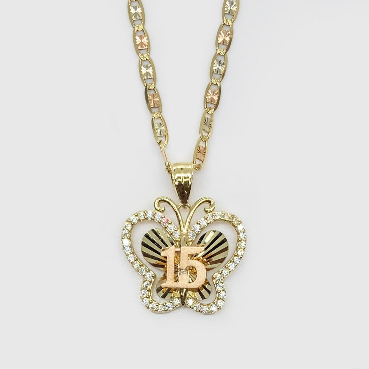 Front view of two-tone gold Quinceañera butterfly pendant featuring CZ stones and 15 detail.