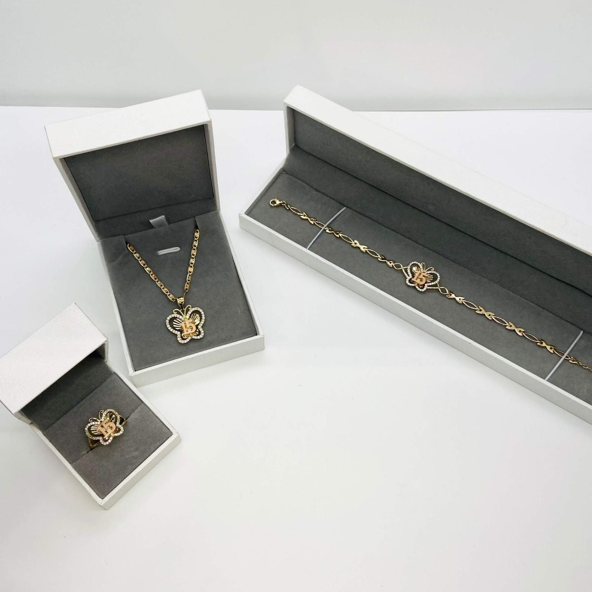 Matching Quinceañera 15th birthday two-tone gold butterfly jewelry set displayed in gift boxes.