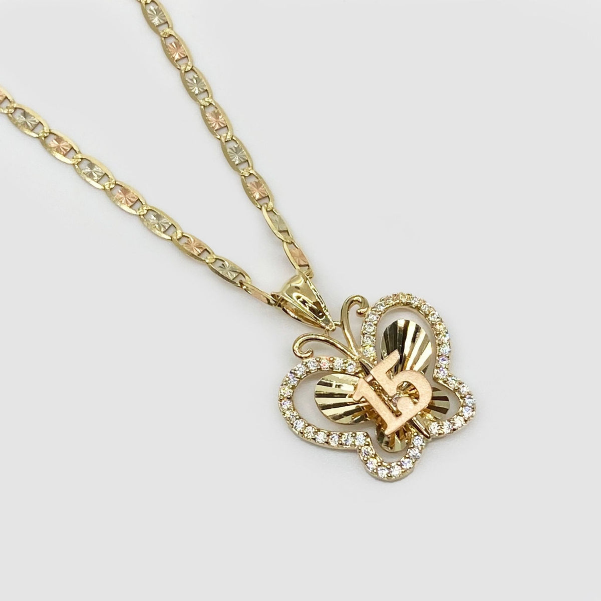 Close-up of CZ stones and gold 15 detail on butterfly pendant.