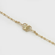 Close-up of a delicate gold butterfly charm chain bracelet on light background.