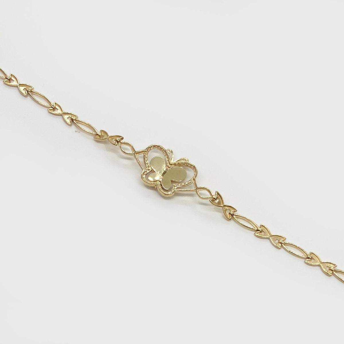 Close-up of a delicate gold butterfly charm chain bracelet on light background.