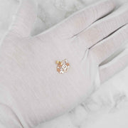White gloved hand holding a tri-color gold Quinceañera 15 heart pendant.