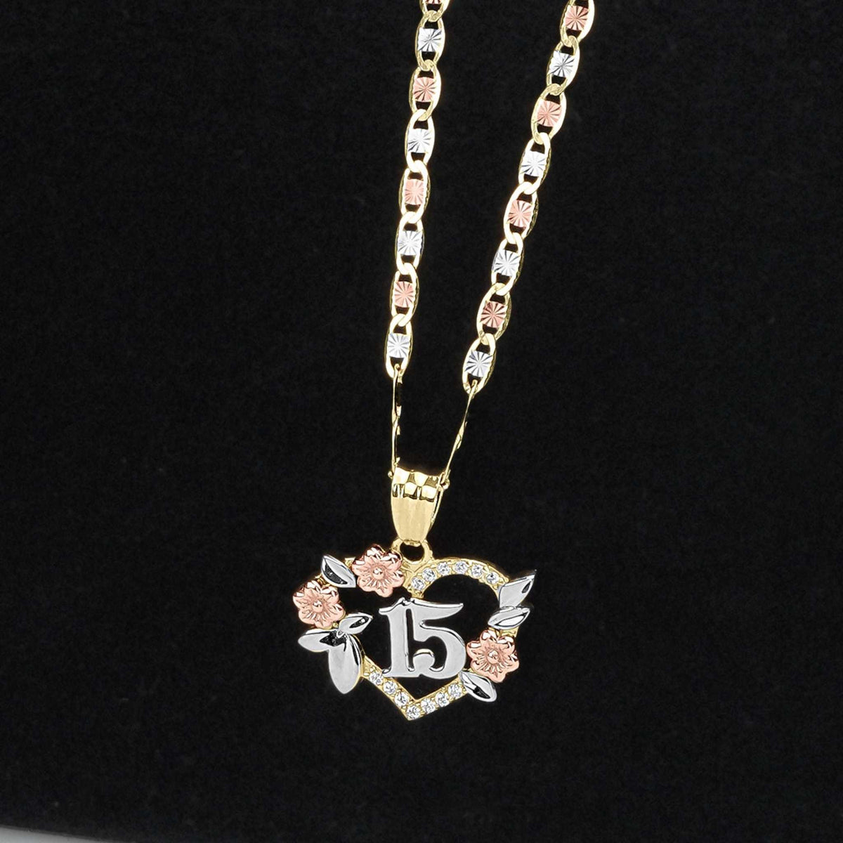 Gold chain necklace with a tri-color Quinceañera 15 heart pendant on a black background.