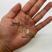 Medium size gold Quinceañera heart wing pendant resting on an open palm.