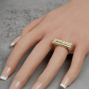 Hand wearing a two-tone gold rectangular ring with diamond-cut details.