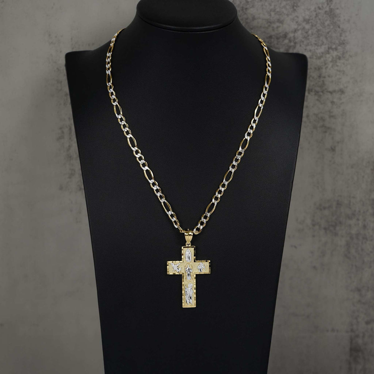 Yellow and white gold religious cross pendant on Figaro chain on black bust
