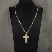 Gold cross pendant with pave stones on Figaro chain, displayed on black mannequin bust.