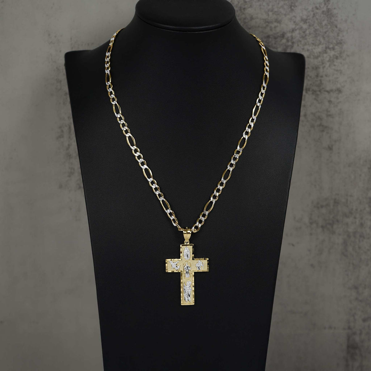 Gold cross pendant with pave stones on Figaro chain, displayed on black mannequin bust.
