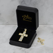 Gold cross pendant in an open black Nolters jewelry box with another pendant beside it.
