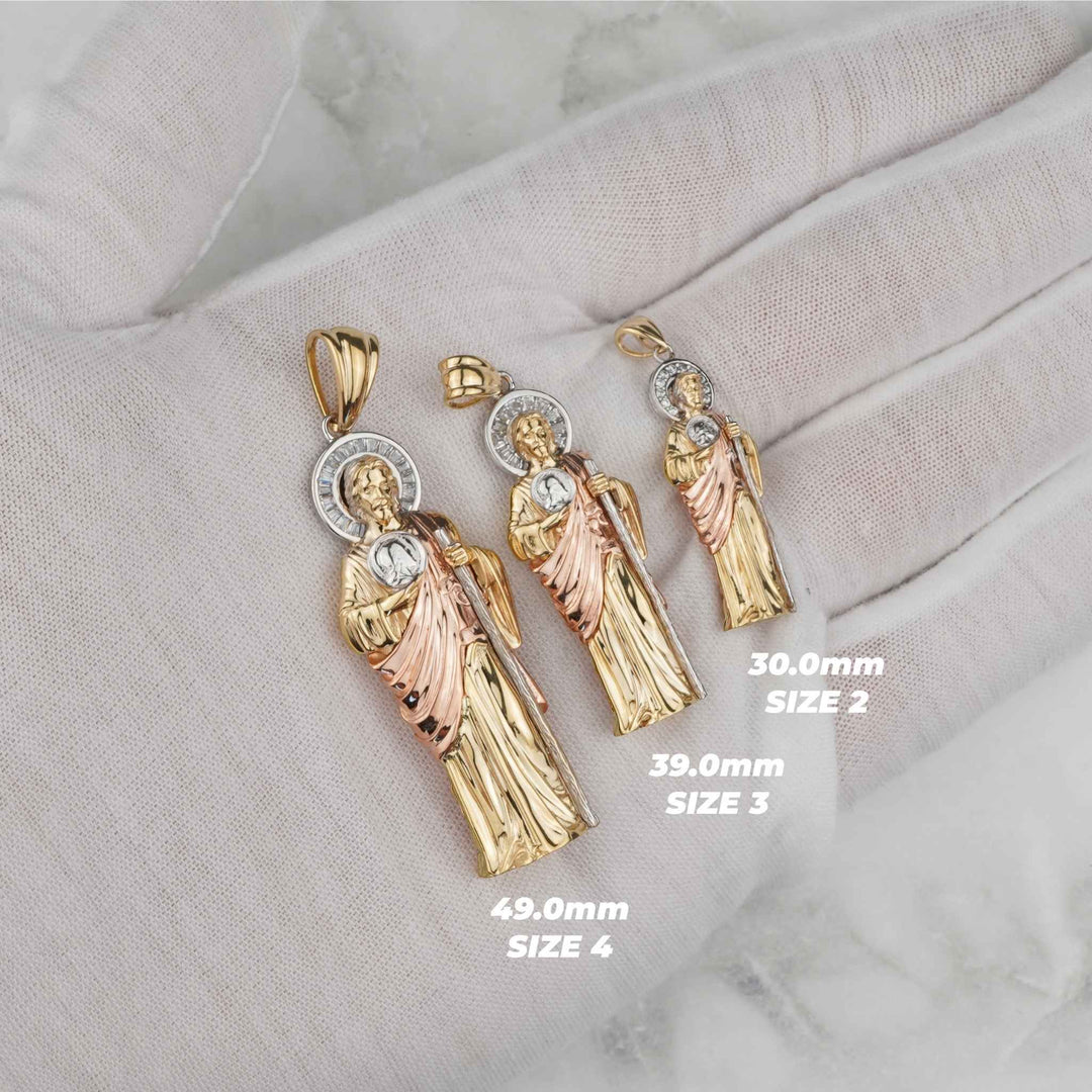White gloved hand displaying three sizes of tri-color gold San Judas pendants.