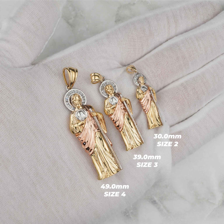 White gloved hand displaying three sizes of tri-color gold San Judas pendants.