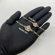 Gloved hand holding small and medium gold Quinceañera crown charm bracelets.