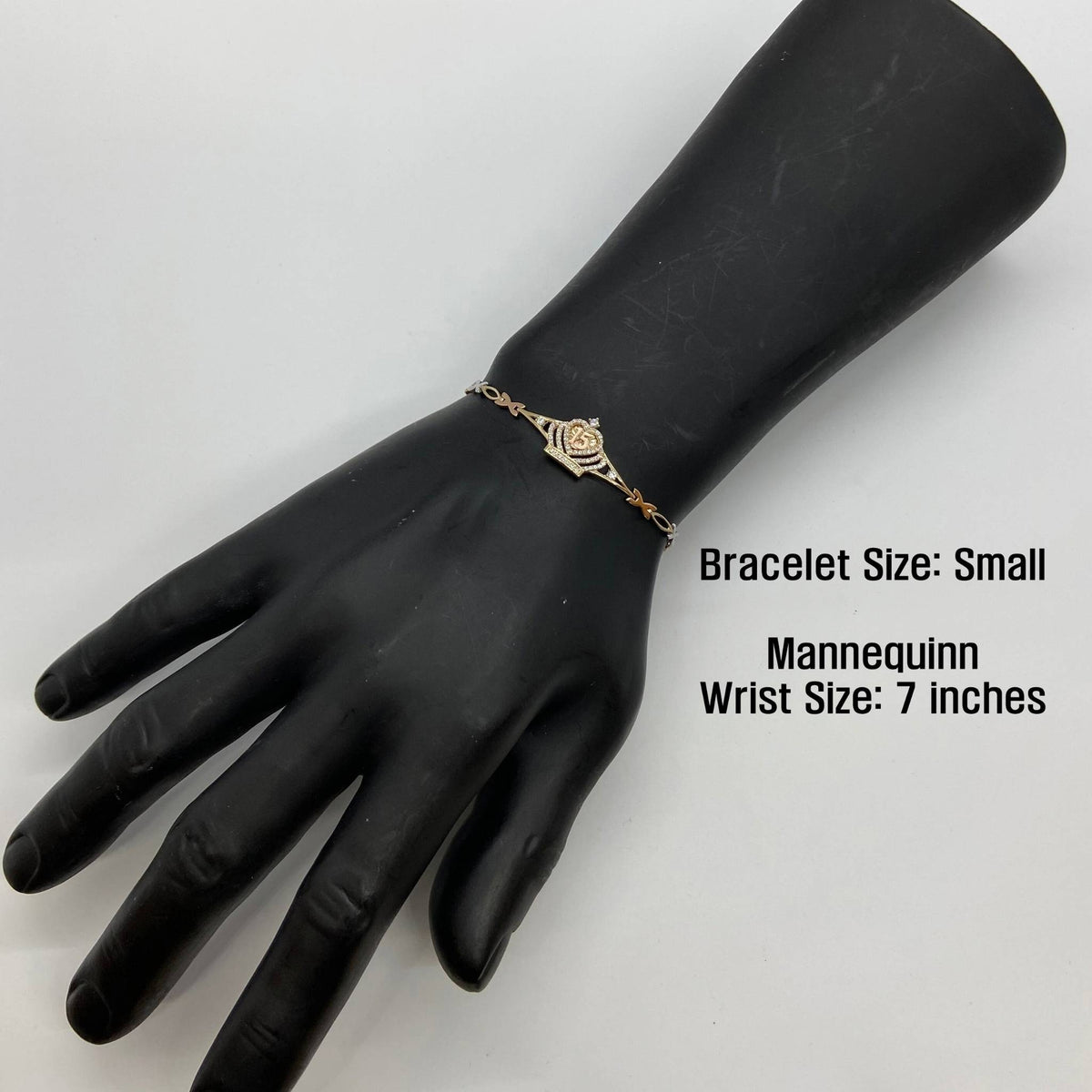 Small gold Quinceañera crown bracelet displayed on a black mannequin hand.