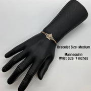 Medium gold Quinceañera crown bracelet displayed on a black mannequin hand.