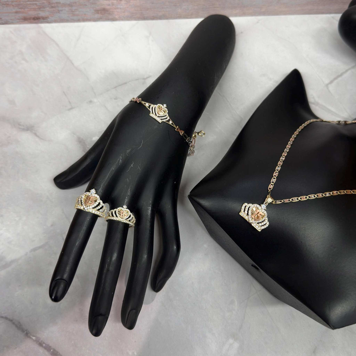 Gold Quinceañera crown jewelry set featuring a bracelet, two rings, and a necklace.