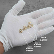 Three labeled sizes of gold Quinceañera royal crown pendants resting on a white gloved hand.