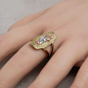 Gold tricolor San Judas rounded rectangle religious signet ring worn on a finger.
