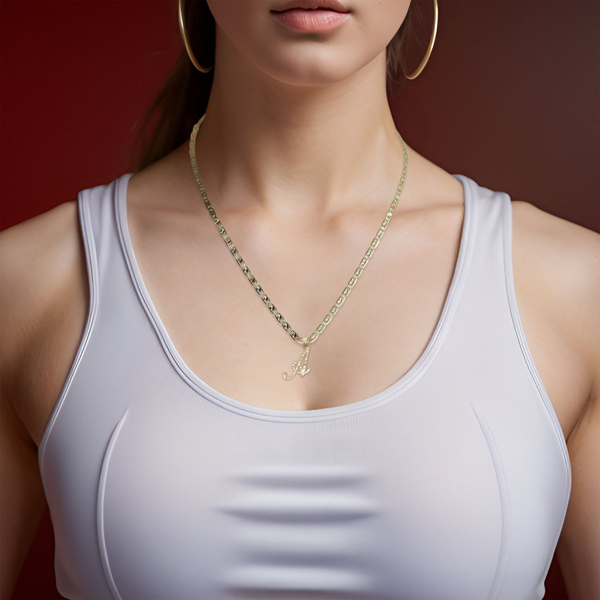 Woman wearing a gold cursive letter A initial pendant necklace on a gold chain.