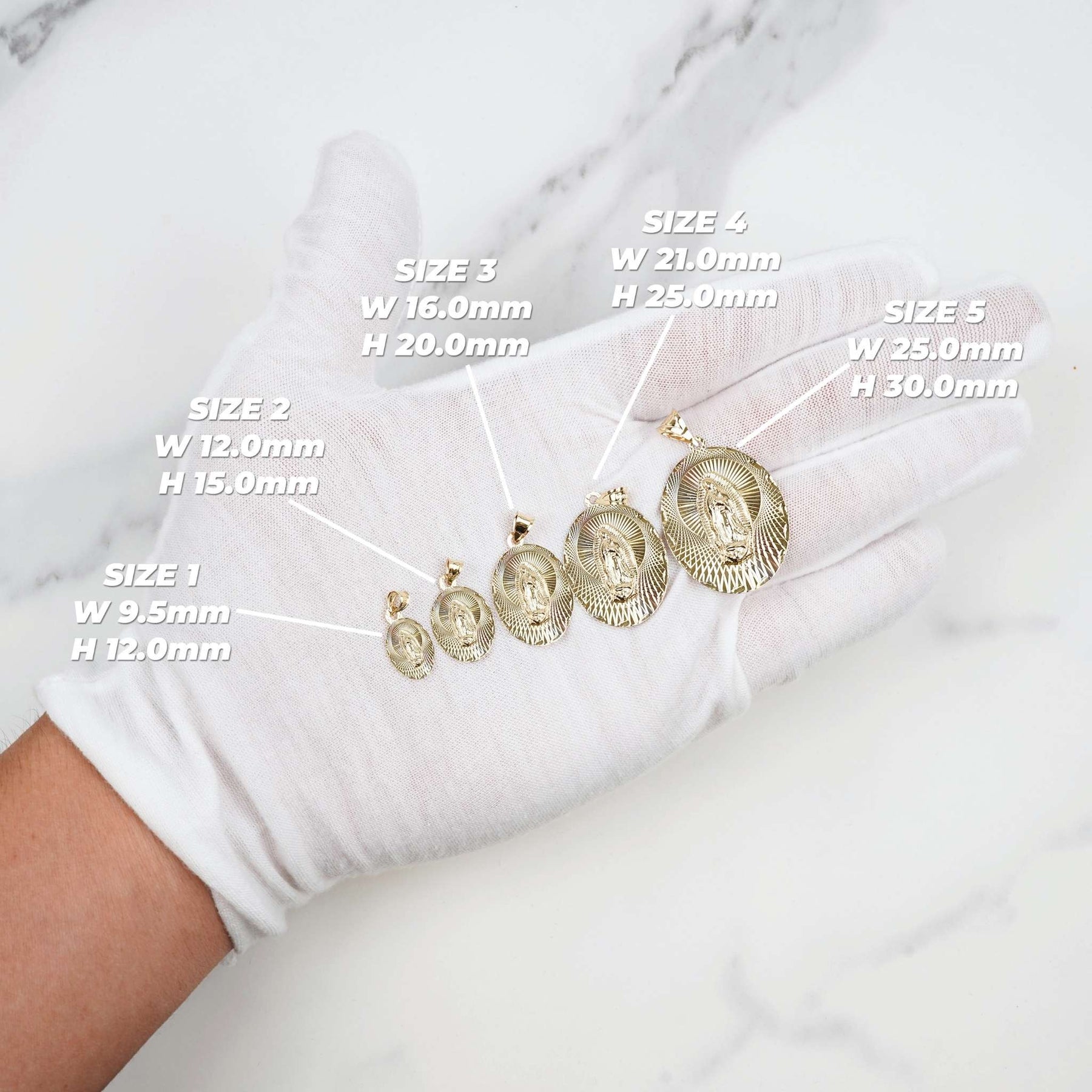 White-gloved hand showcasing five different sizes of gold Virgin Mary oval pendants.