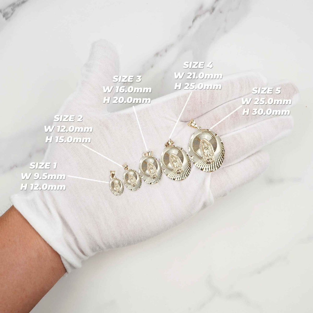 Gloved hand holding five gold Virgin Mary pendants in size order on marble.