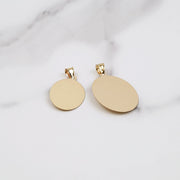 Back view of two smooth yellow gold Virgin Mary oval pendants on marble.