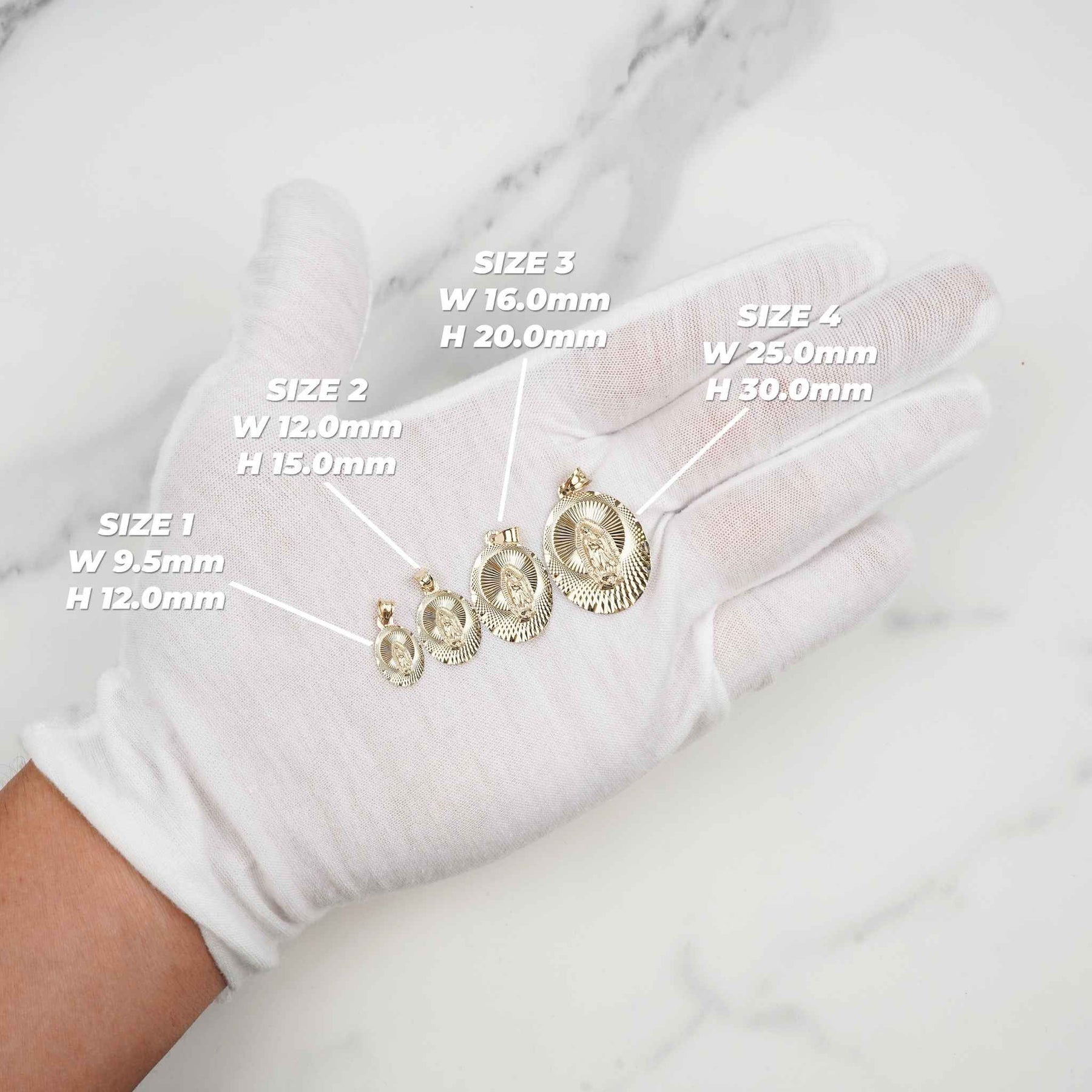 Gloved hand holding yellow gold Virgin Mary oval pendants showing different size options.
