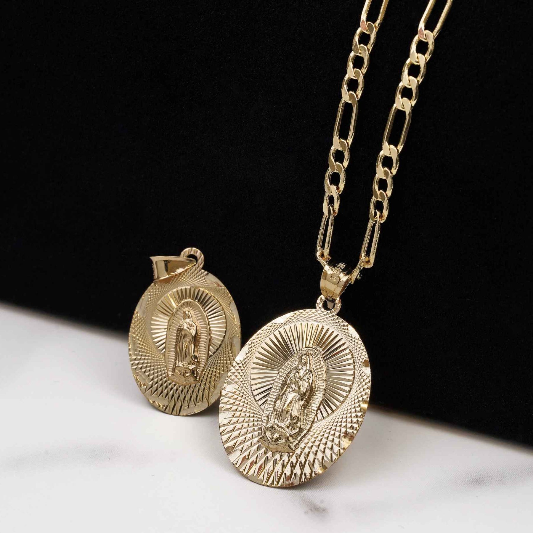 Two yellow gold Virgin Mary oval pendants, one attached to a Figaro chain.