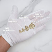 Five different sizes of round gold Virgin Mary pendants displayed on a hand.