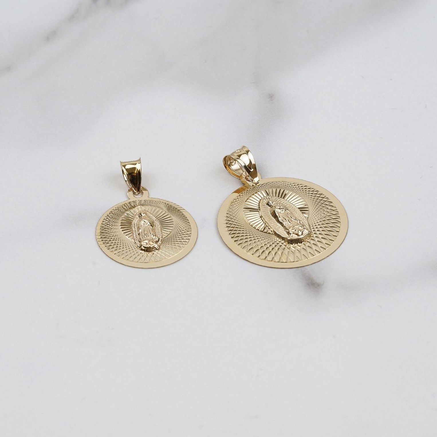 Gold Virgin Mary pendant necklace with a matching round medallion on display.