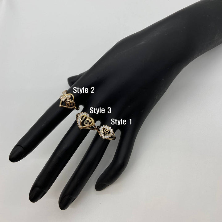 Black mannequin hand wearing three gold Sweet 16 Heart Ring with different designs.