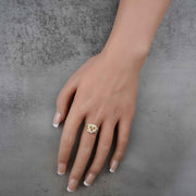 Hand wearing a 10k - 14k gold ring with a heart and number 15 design on a gray background