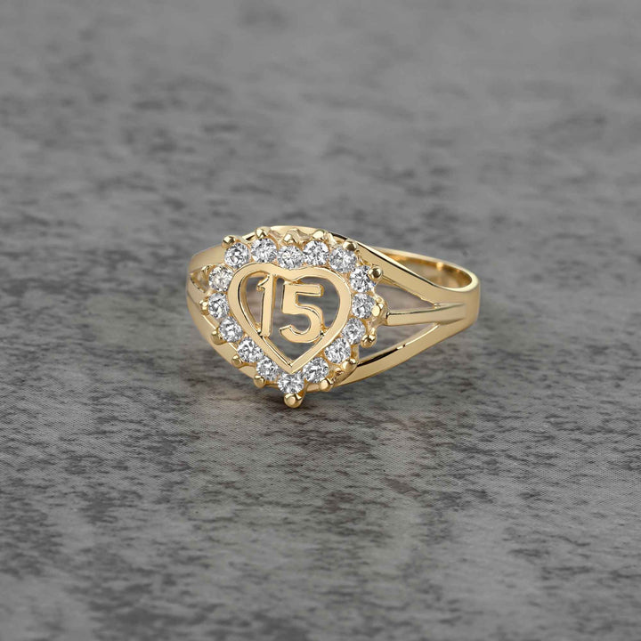 10k - 14k Gold ring with heart design and number 15 on a gray surface