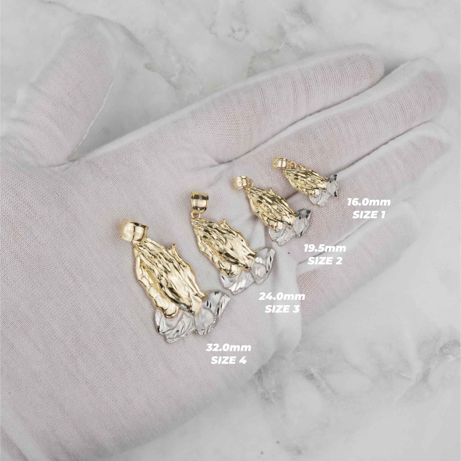 Four gold praying hands pendant sizes displayed on a white gloved hand.