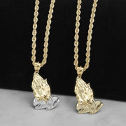 Two-tone and yellow gold praying hands pendants hanging on gold rope chains.