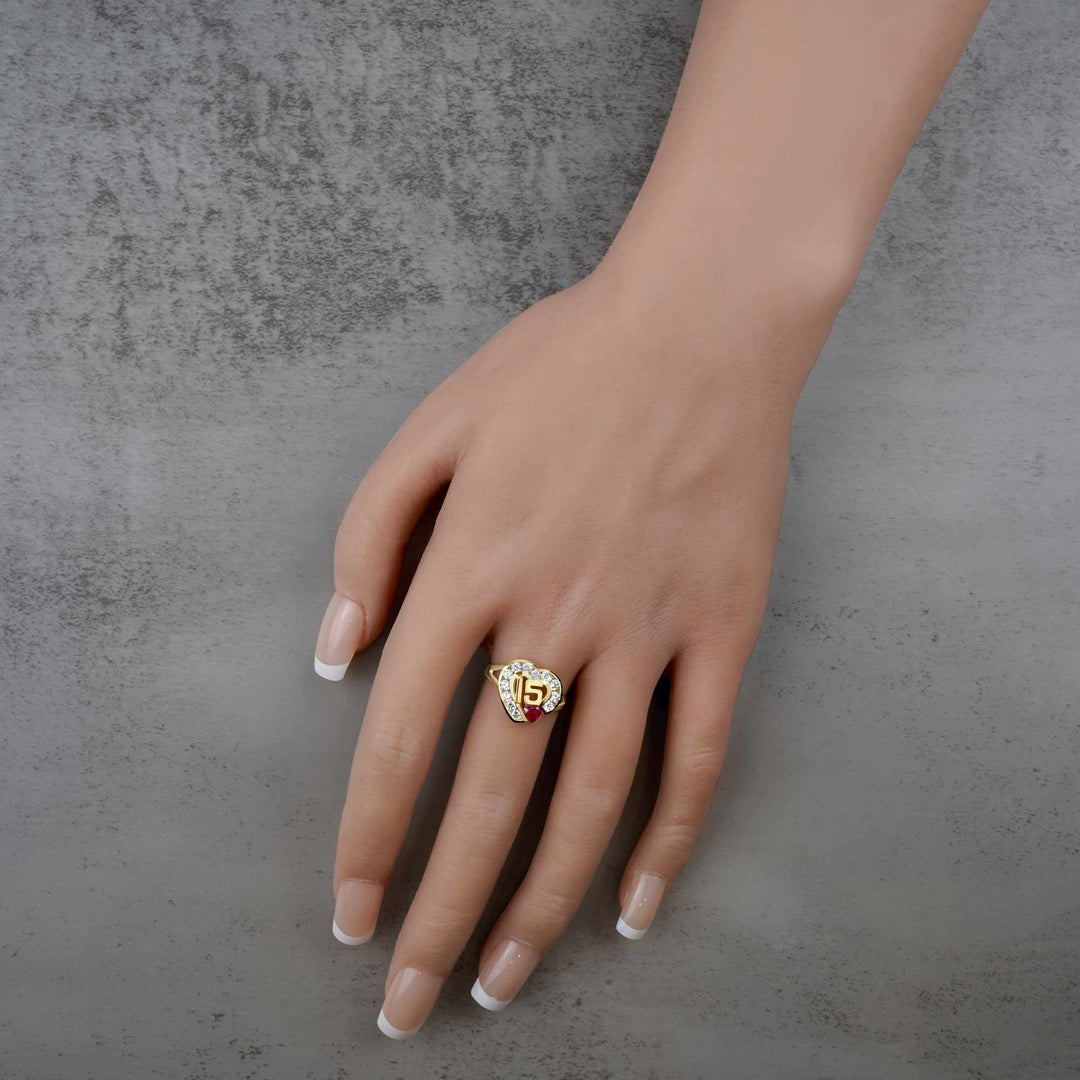 Hand wearing a 10k - 14k Quinceanera ring with a number 15 on a gray background
