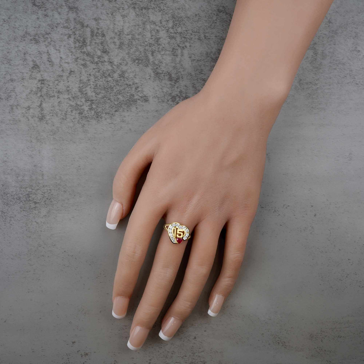 Hand wearing a 10k - 14k Quinceanera ring with a number 15 on a gray background