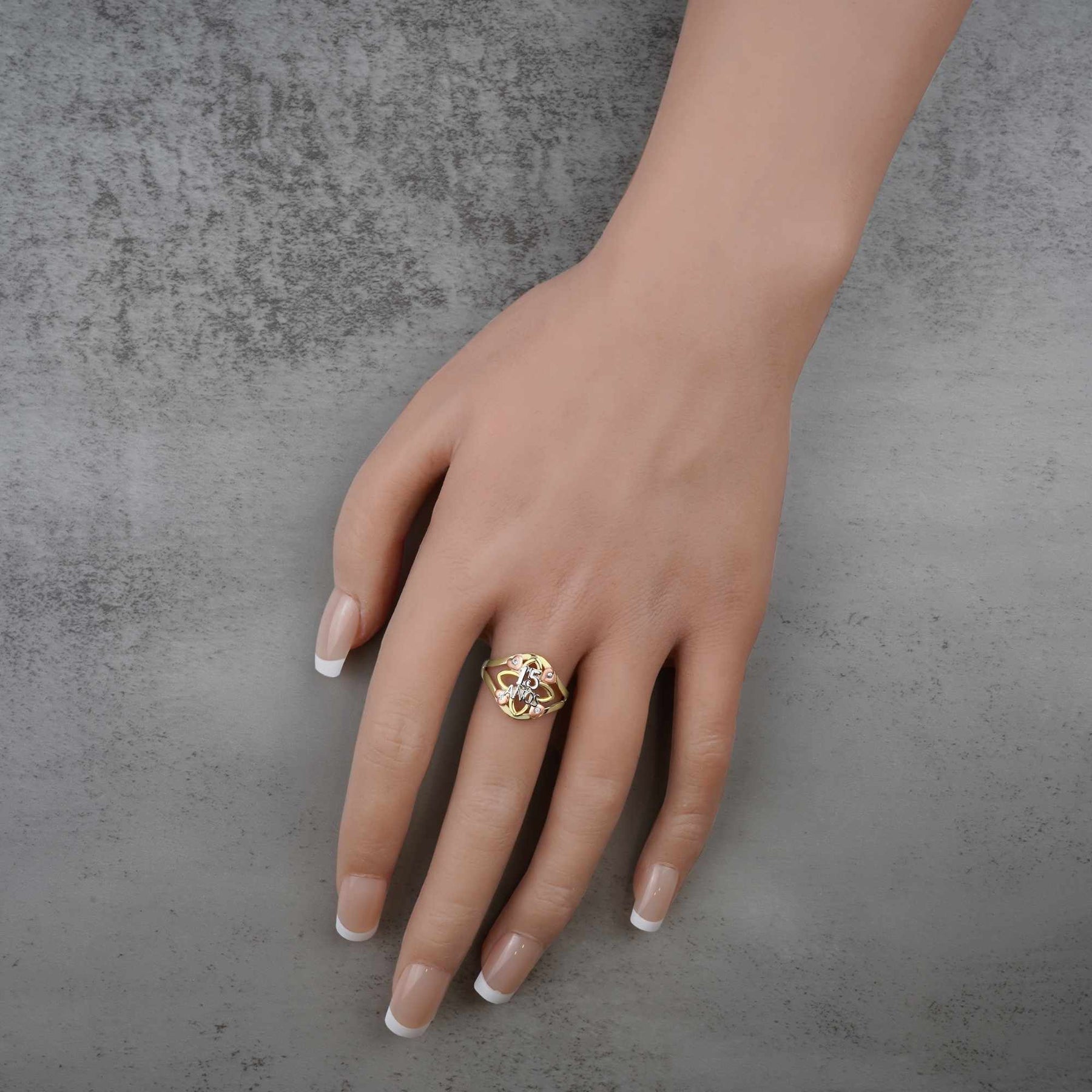Hand wearing a 10k - 14k tricolor gold ring with a 15 anos engraving design 
