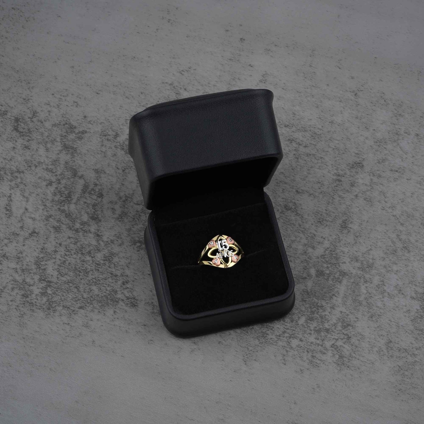 10k - 14k tri color gold ring in a black jewelry box on a gray concrete surface