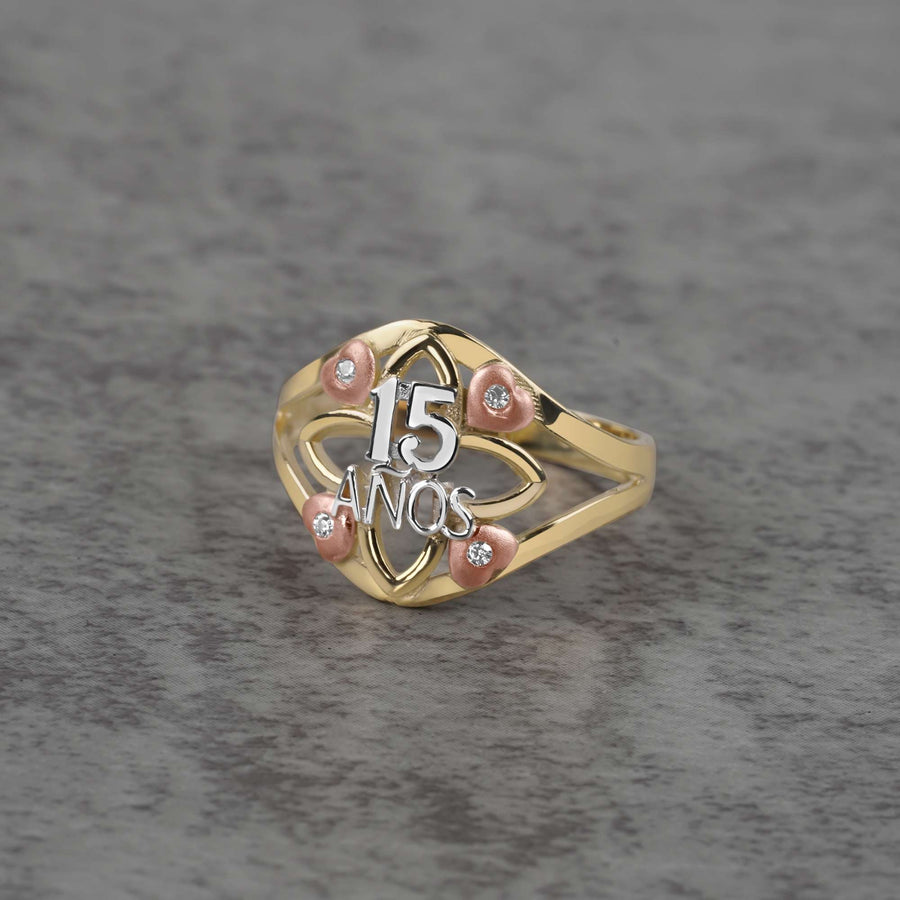 10k - 14k tricolor gold ring with 15 anos engraving on a gray surface