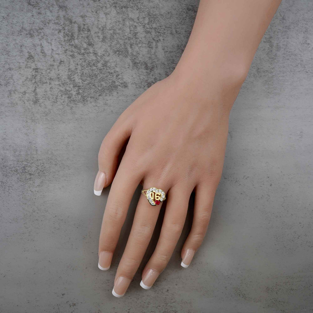 Hand wearing a 10k - 14k gold ring with a red cubic zirconiaon a gray background