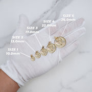 Five varying sizes of tricolor gold Virgin Mary pendants displayed on a white gloved hand with measurement labels.