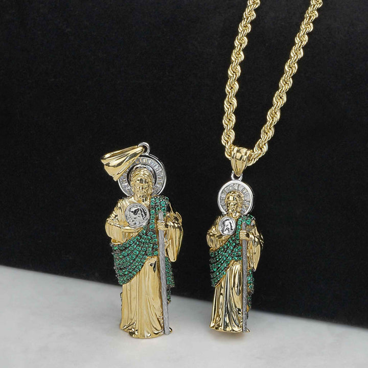 Two two-tone gold San Judas pendants with green stones, one on a rope chain.